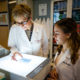 Sabra Klein and Janna Shapiro look at a specimen on a lightbox.